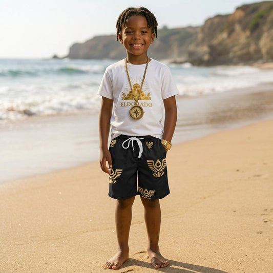 A boy wearing Eldorado Kidz black polyester beach shorts with gold wing patterns and an elastic drawstring waist.