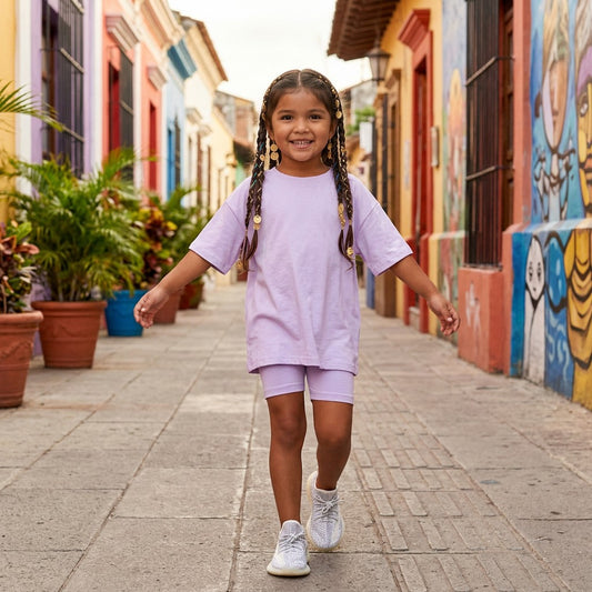 Eldorado Kidz girl wearing a loose-fit lavender cotton T-shirt and matching shorts set on a colorful street.